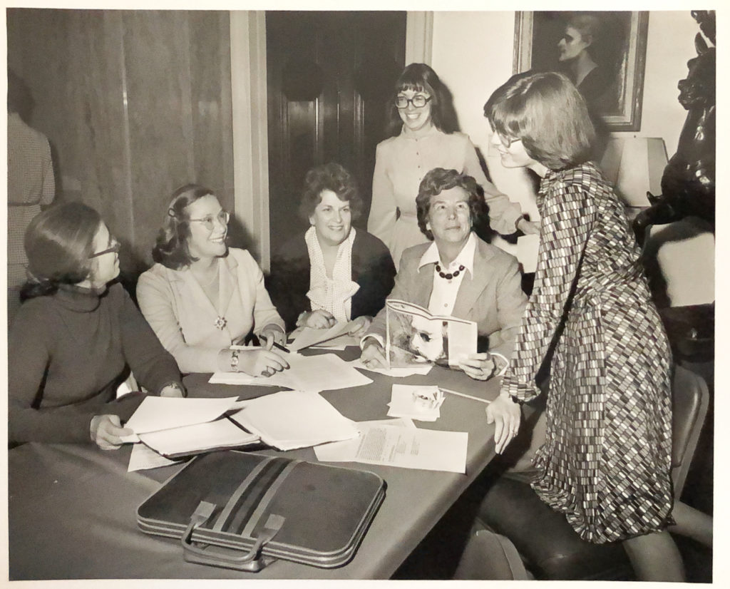 Multiple women members of AAFSW gathered around a table that is covered with documents
