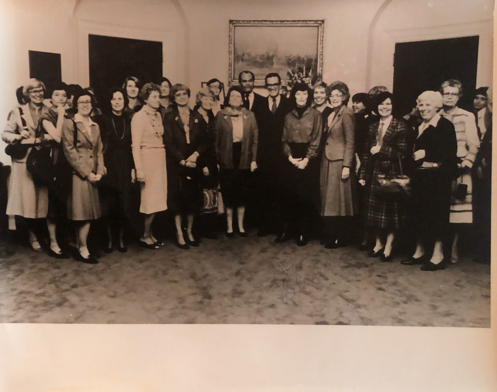 Group of women standing together and posed for a photo in the Roosevel Room of the White House